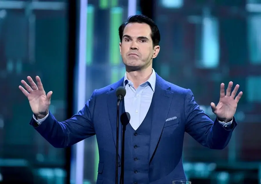 Jimmy Carr at Big Belly Comedy Club A man in a blue suit with his hands outstretched.