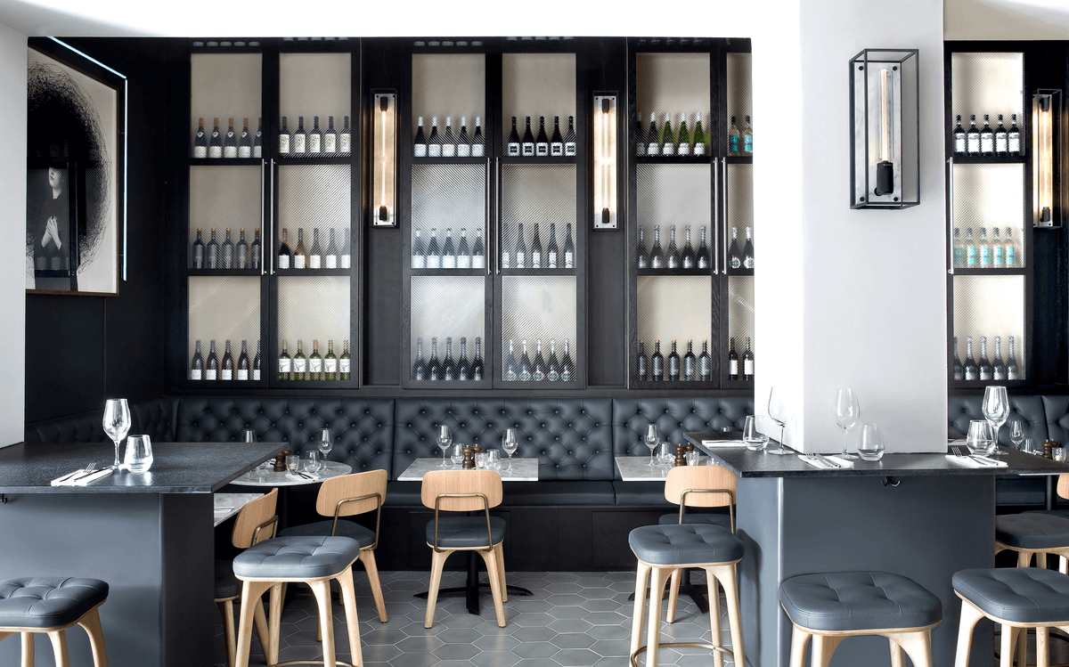 Black and white restaurant with wine bottles on the wall.