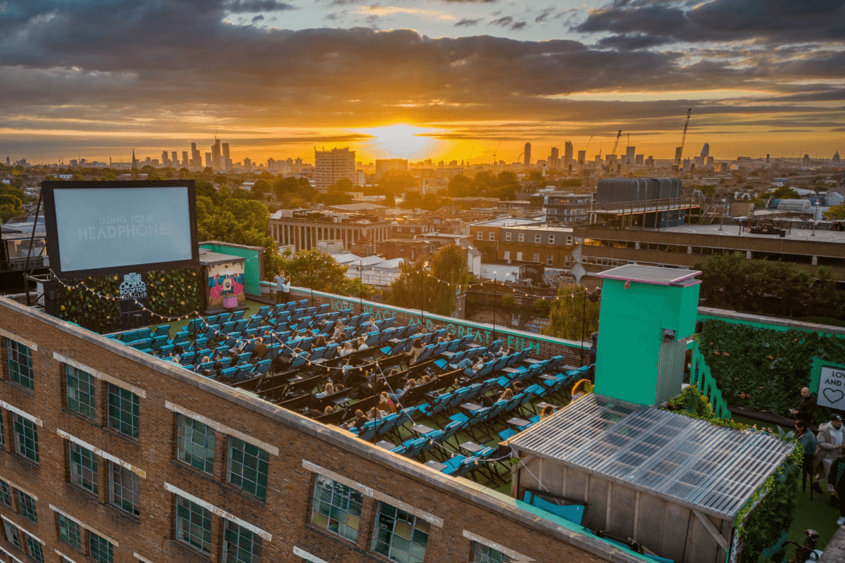 A rooftop cinema with people watching a movie in london.