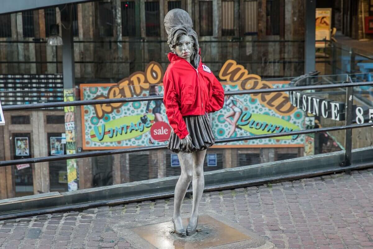 A statue of a woman in a red jacket standing in front of a building.