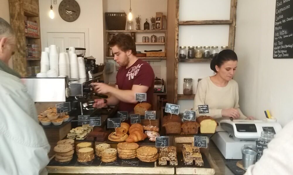 A group of people standing at the counter of a bakery.