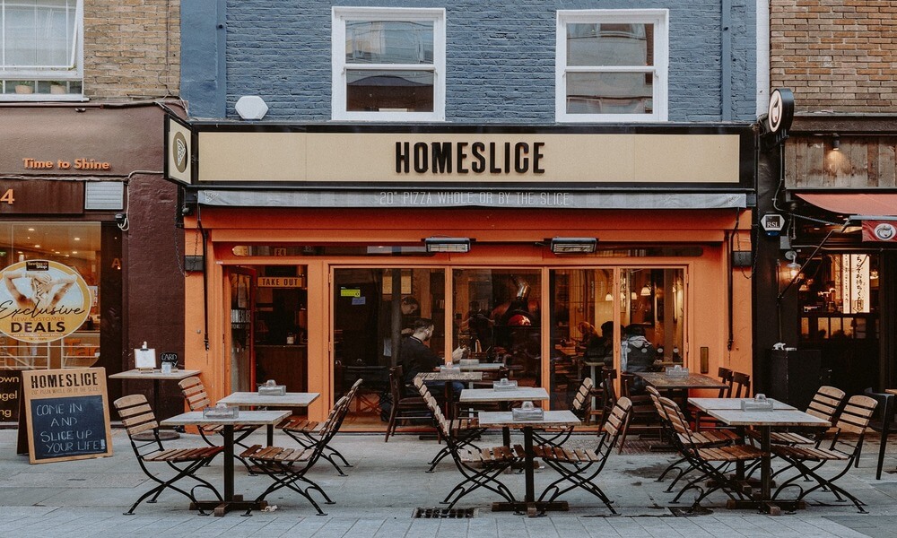 A restaurant with tables and chairs on a street in london.