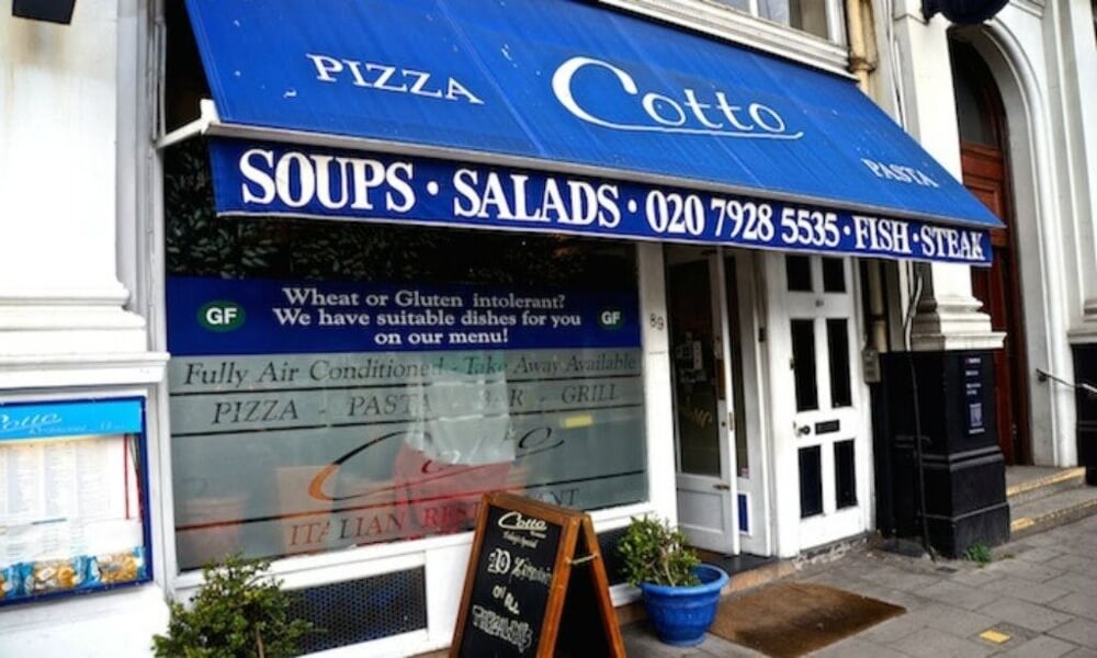 A restaurant with a blue awning and a sign that says coto soups salads.