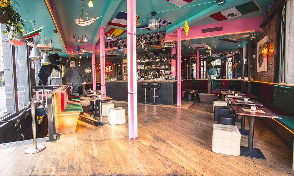 A colorful bar with wooden floors and colorful walls.