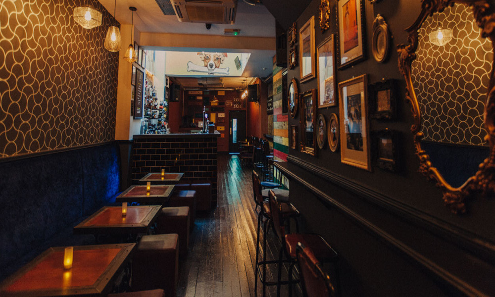 A narrow bar with stools and pictures on the wall.