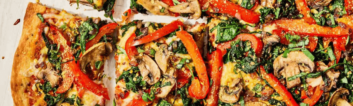 A pizza with spinach, mushrooms and peppers.