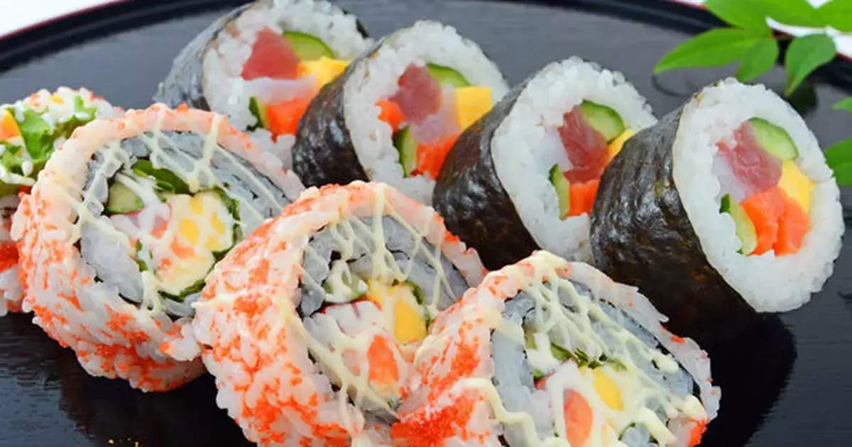 Japanese sushi rolls on a black plate.