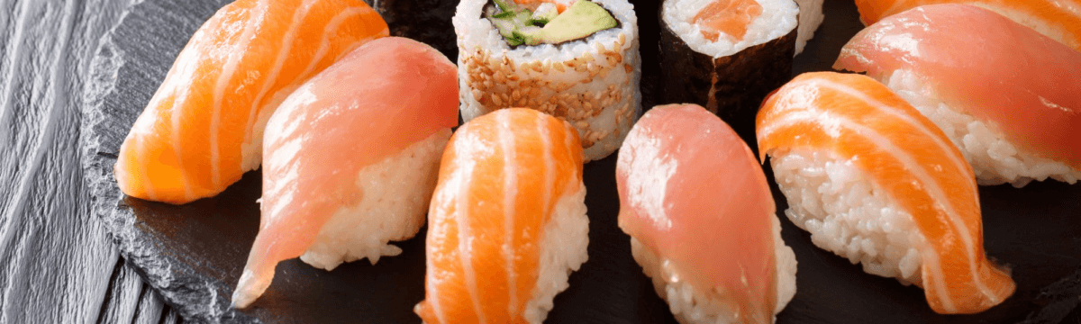 Sushi and sashimi on a black plate.