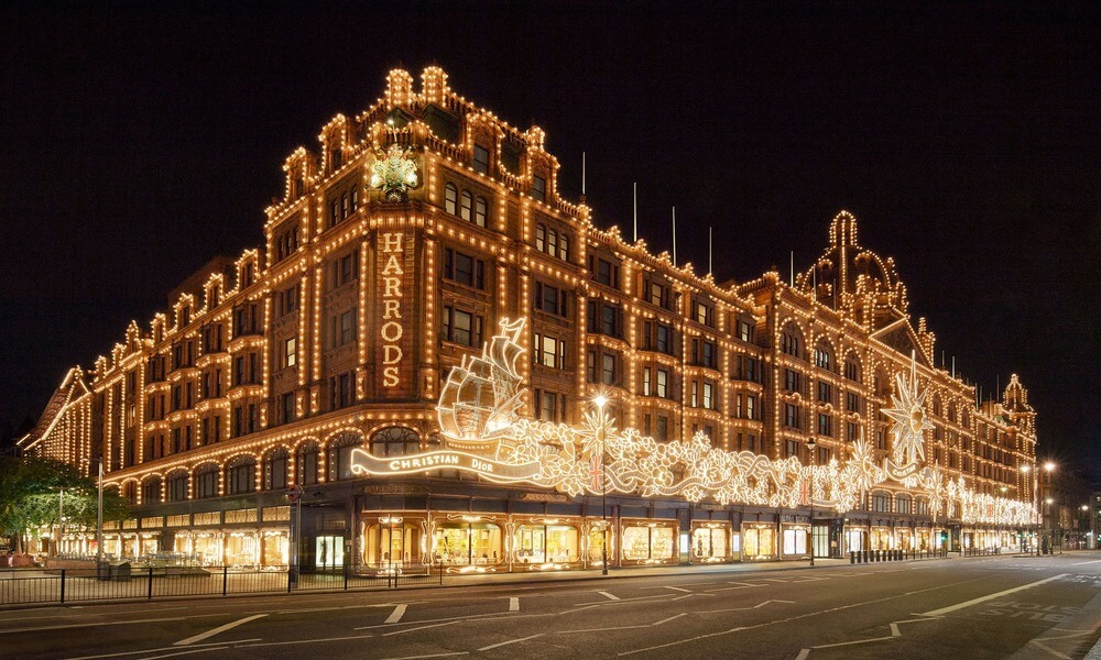 The harrods store in london is lit up at night.