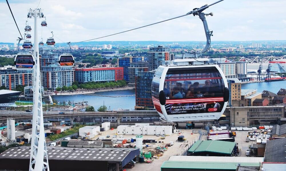 A cable car is flying over a city.