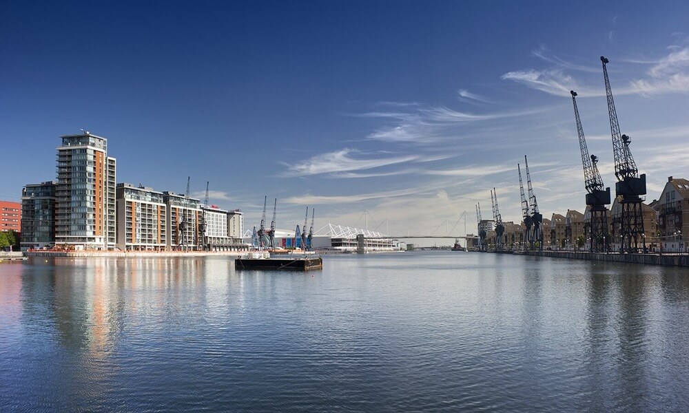 The river thames in london with cranes in the background.