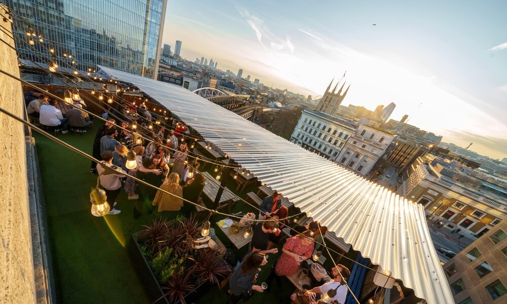 A group of people are sitting on a rooftop in london.