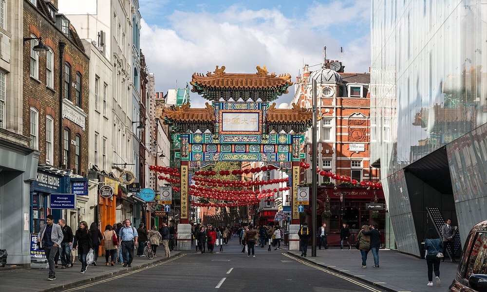 A street with a chinese gate and people walking down the street.