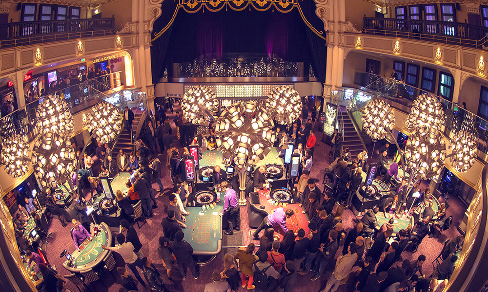 A crowd of people at a casino in a large hall.