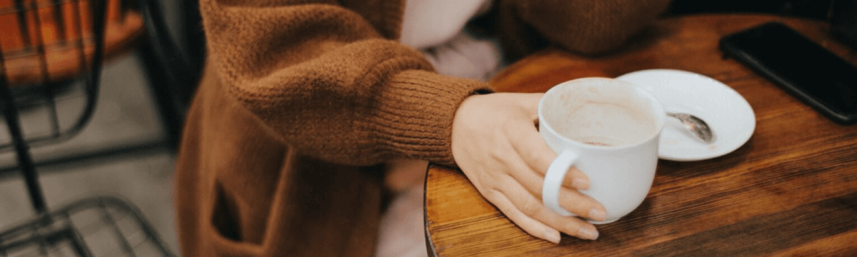 A woman's hand holding a cup of coffee.