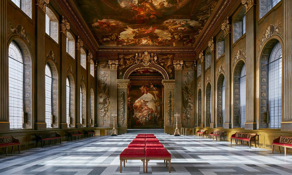An ornate room with red benches and paintings.