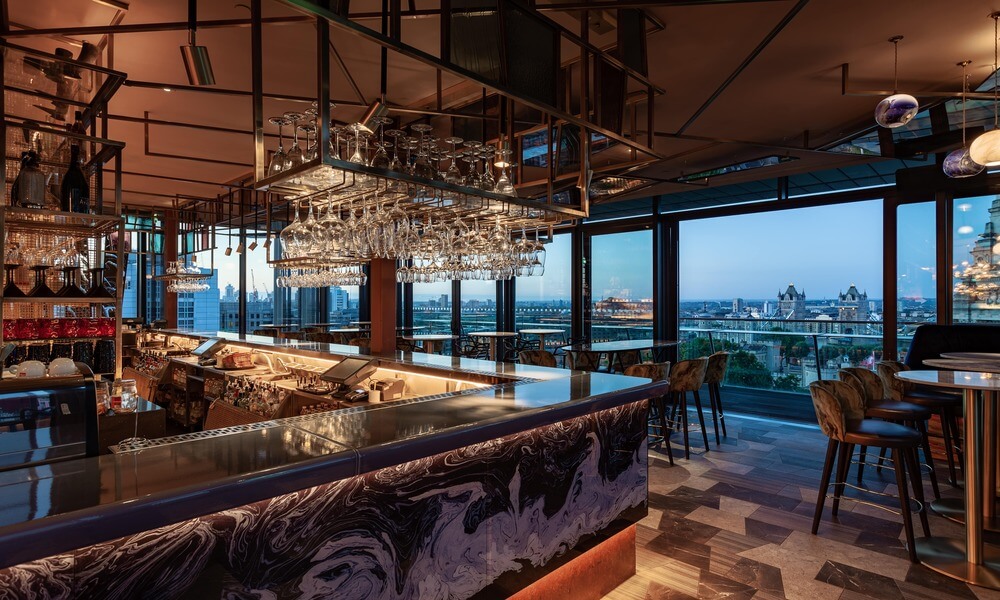 A bar with a view of the city at dusk.
