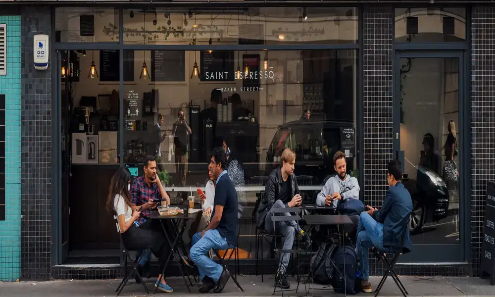 A group of people sitting outside of a coffee shop.