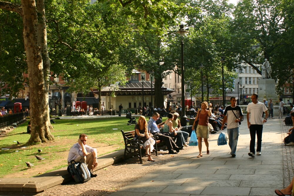 A group of people sitting on a bench in a park.