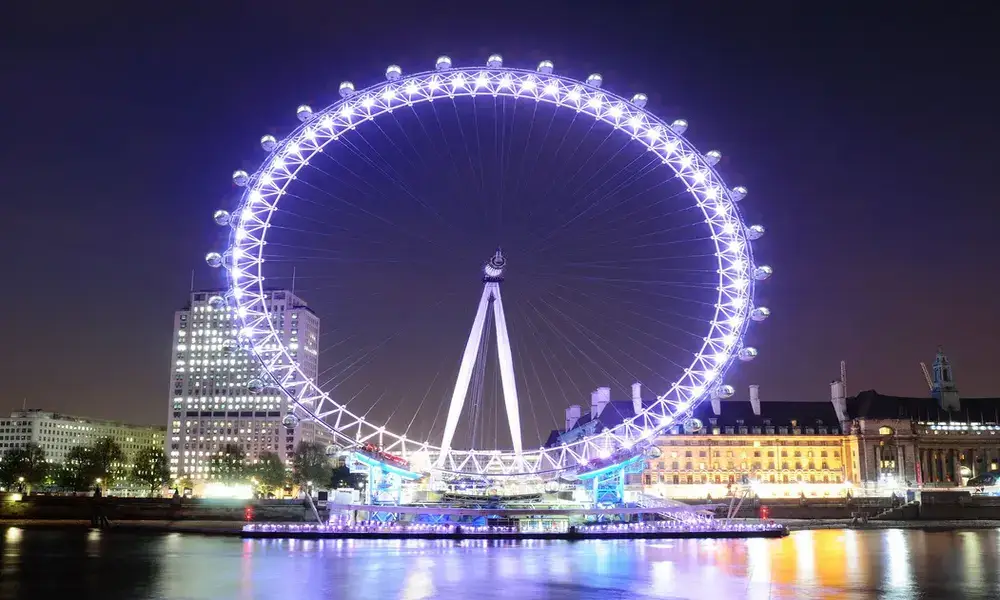 The london eye is lit up at night.