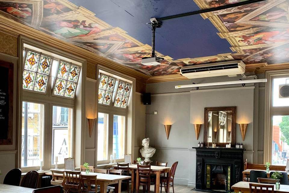 A restaurant with a painted ceiling and windows.