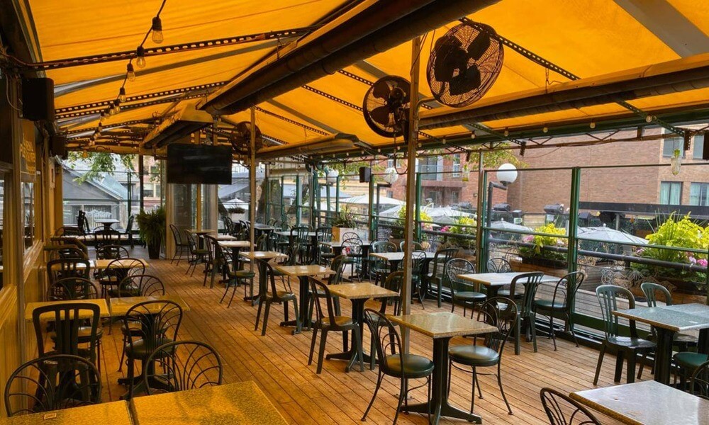 A restaurant with tables and chairs under a yellow awning.