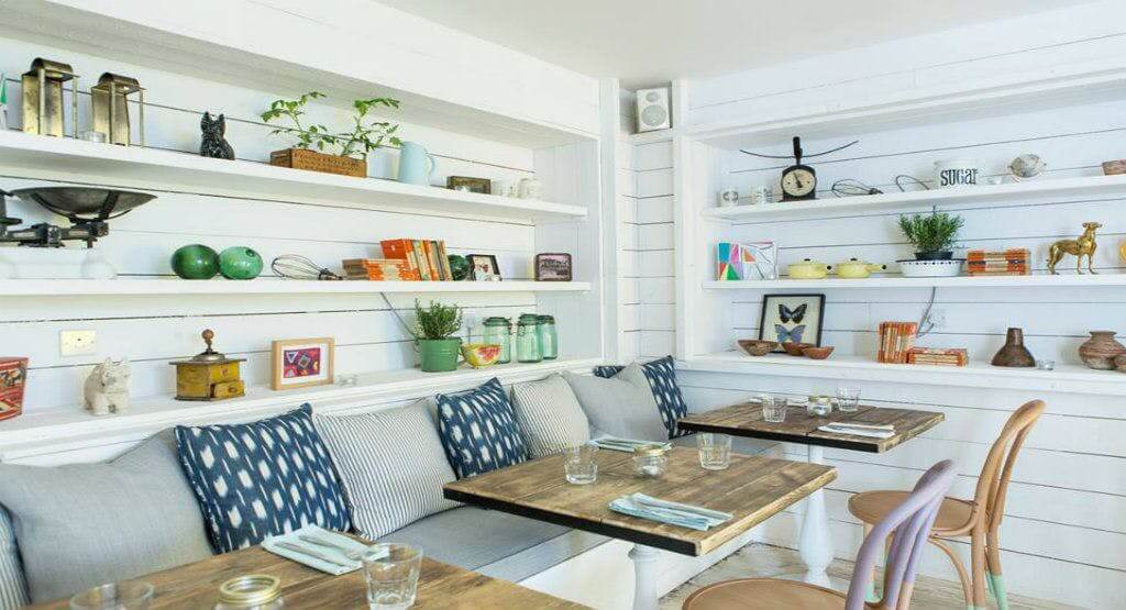 A white dining room with wooden tables and shelves.