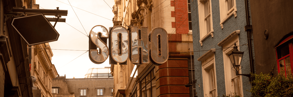 A sign that says soho hanging from a building.