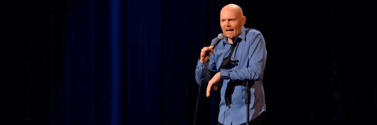 A bald man with a microphone on stage.