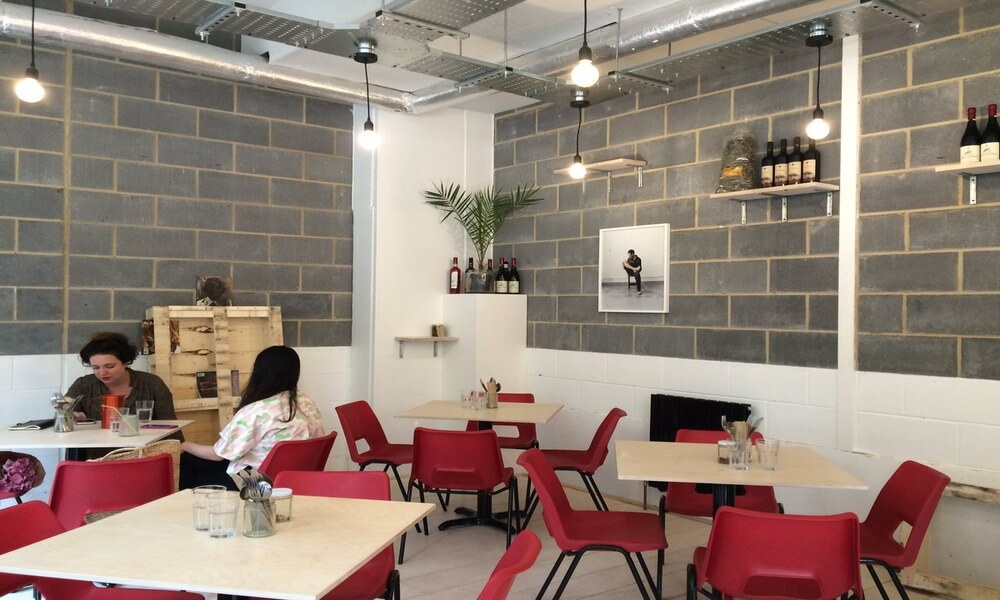 The interior of a restaurant with red chairs and a brick wall.