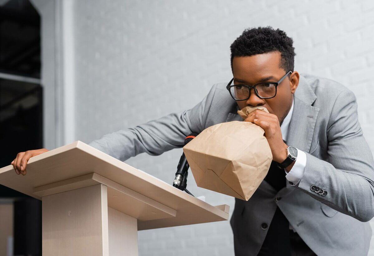 A businessman eating a paper bag in front of a podium.