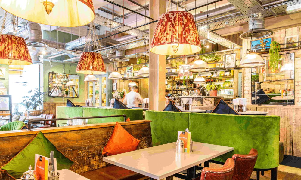 The interior of a restaurant with green booths and tables.