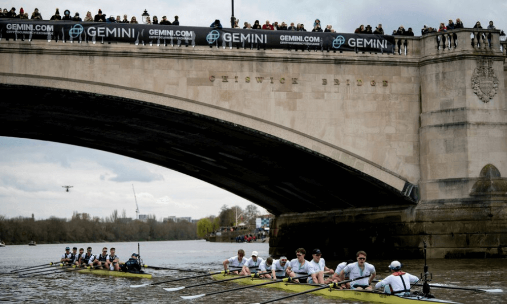 A group of rowers rowing under a bridge in london.
