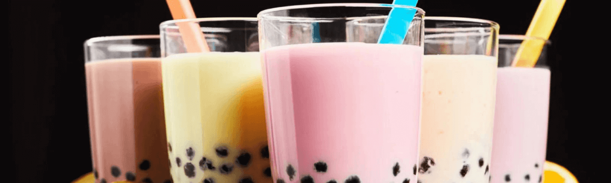 A group of bubble tea drinks with straws on a black background.