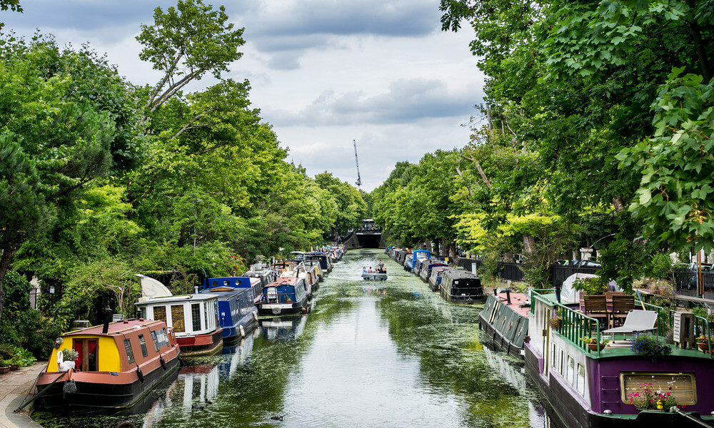 A canal lined with boats and trees.