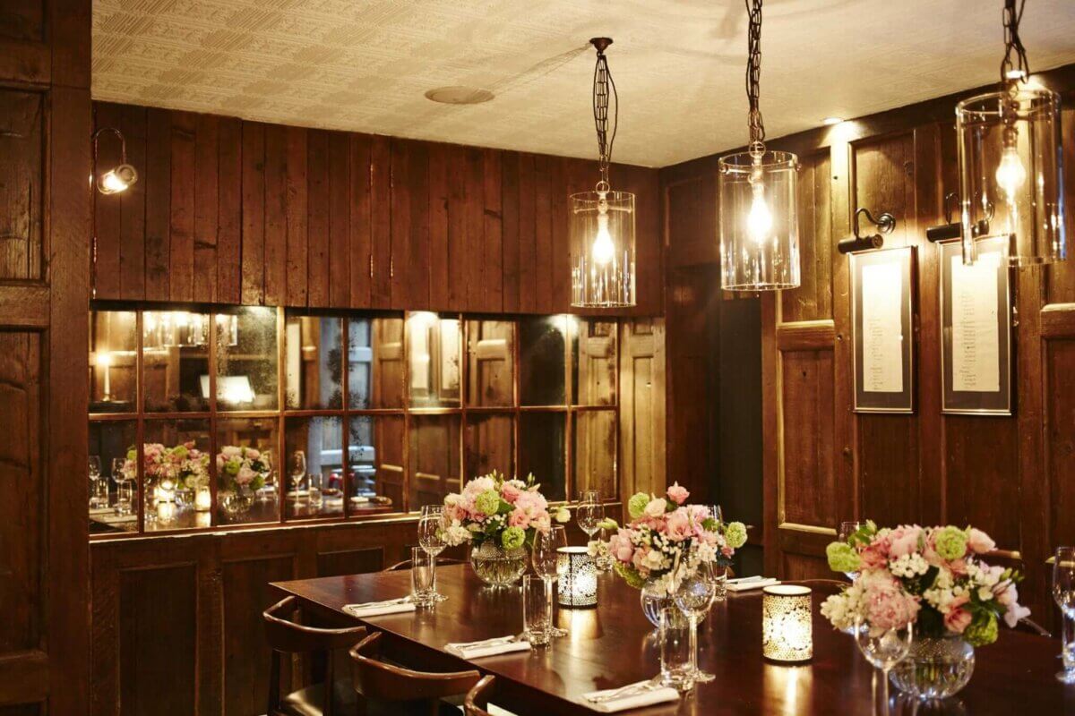 A wood paneled dining room with candles and flowers.