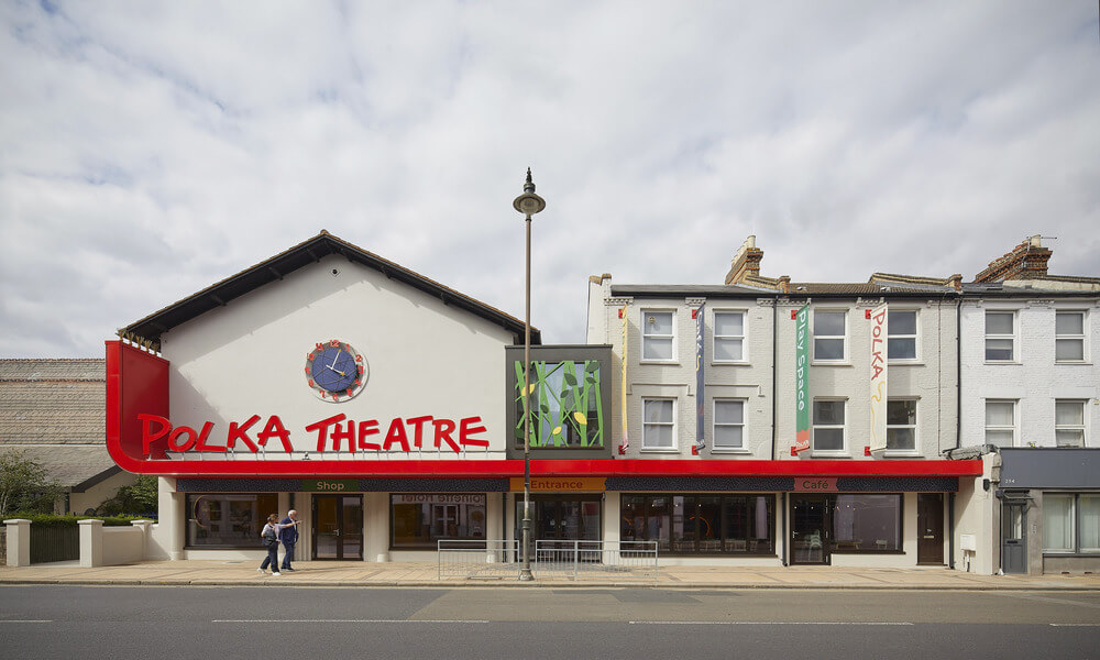 A red and white building with a sign that reads polka theatre.