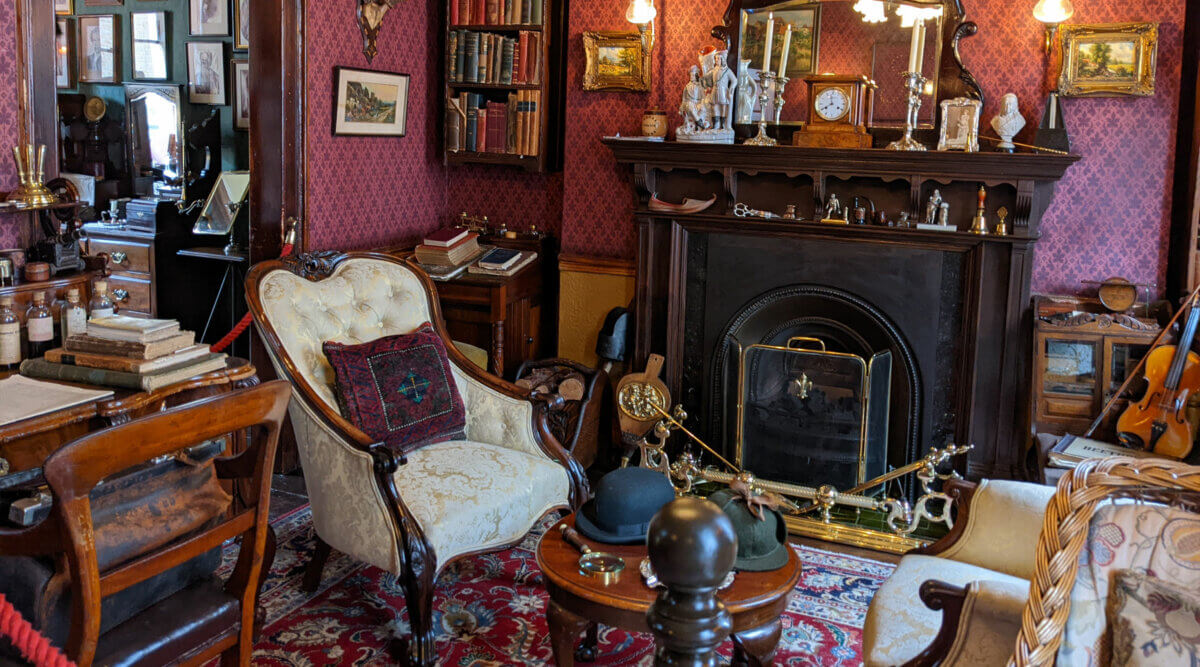 A victorian living room with antique furniture and a fireplace.