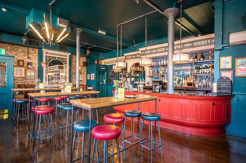 A blue and red bar with stools and a wooden floor.