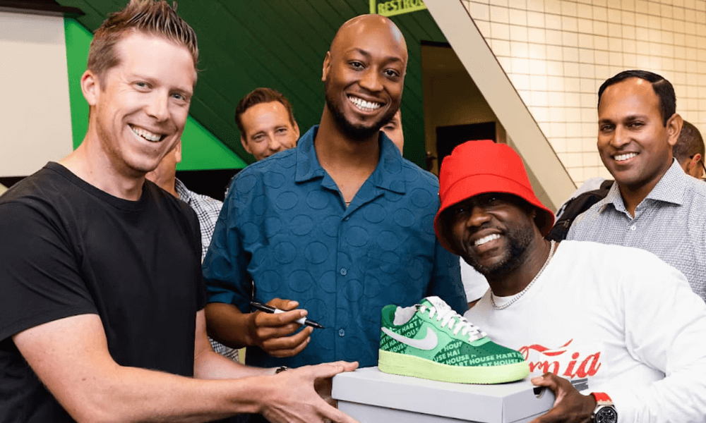 Four men smiling at an event, one holding a green sneaker.