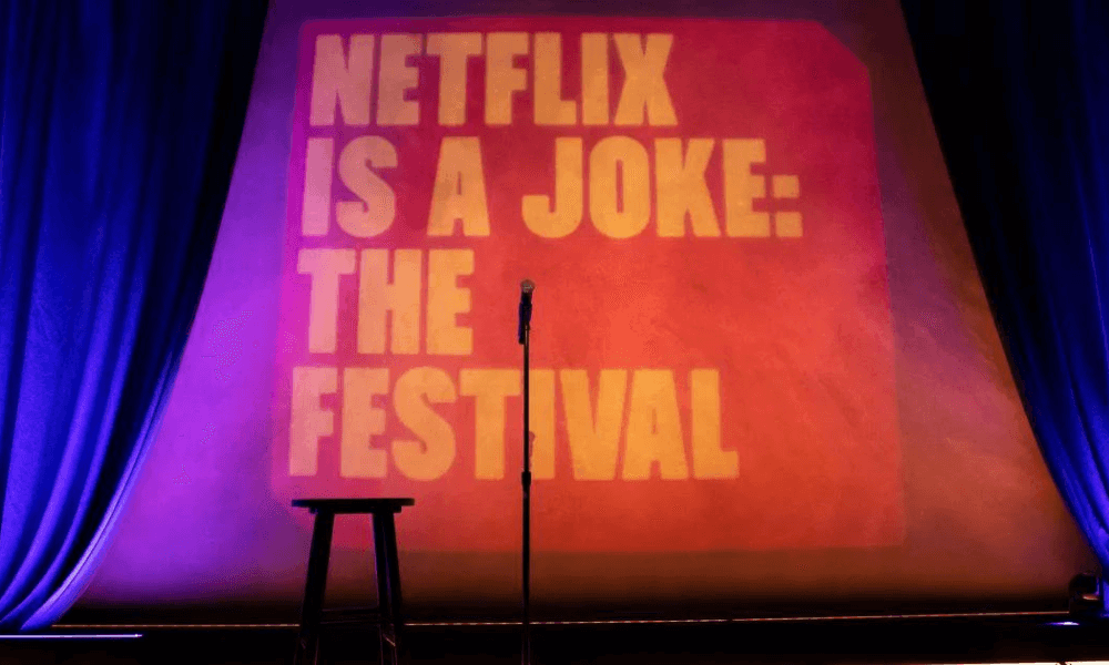 A microphone stand on a stage with a backdrop displaying "netflix is a joke: the festival".