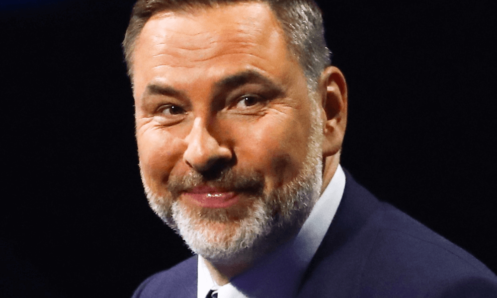 Man with a beard smiling in a blue suit.