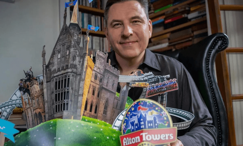 Man sitting beside a detailed miniature model of alton towers theme park.