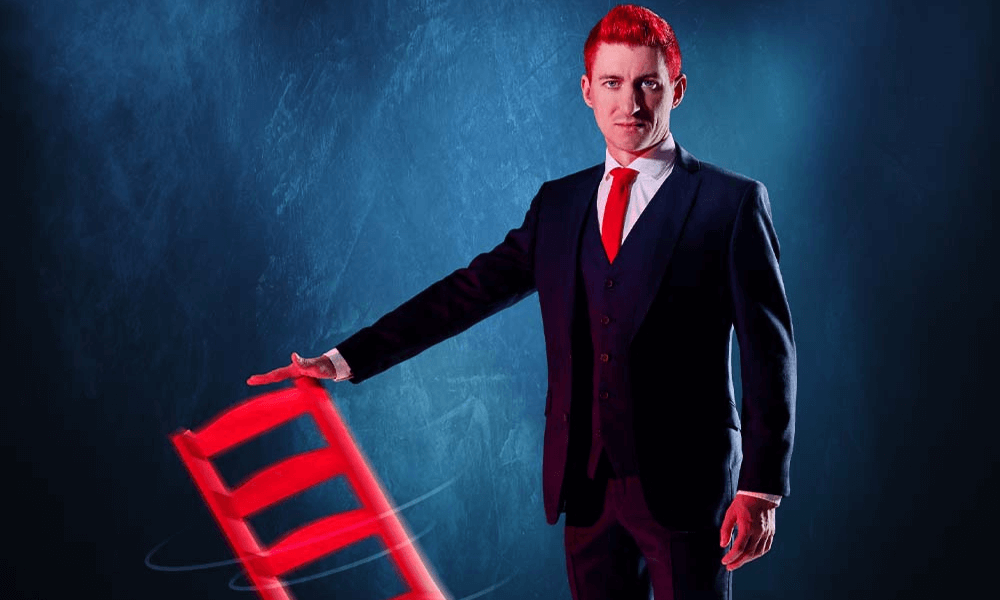 A man in a suit holding a glowing red chair with a dark background.
