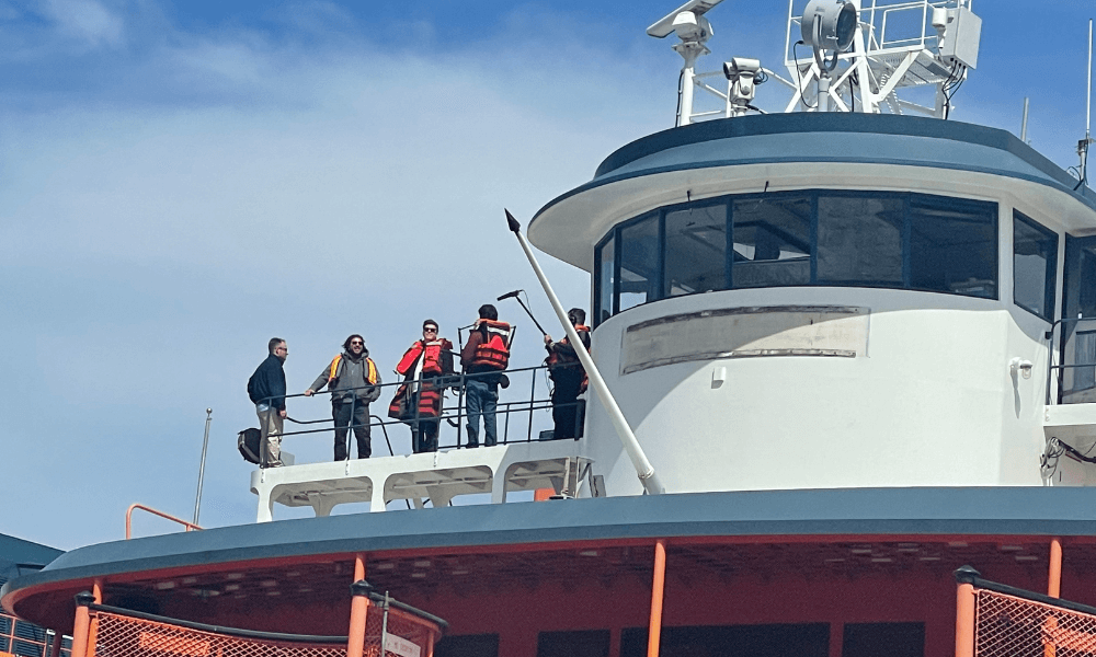 Crew members on the deck of a boat engaged in a discussion.