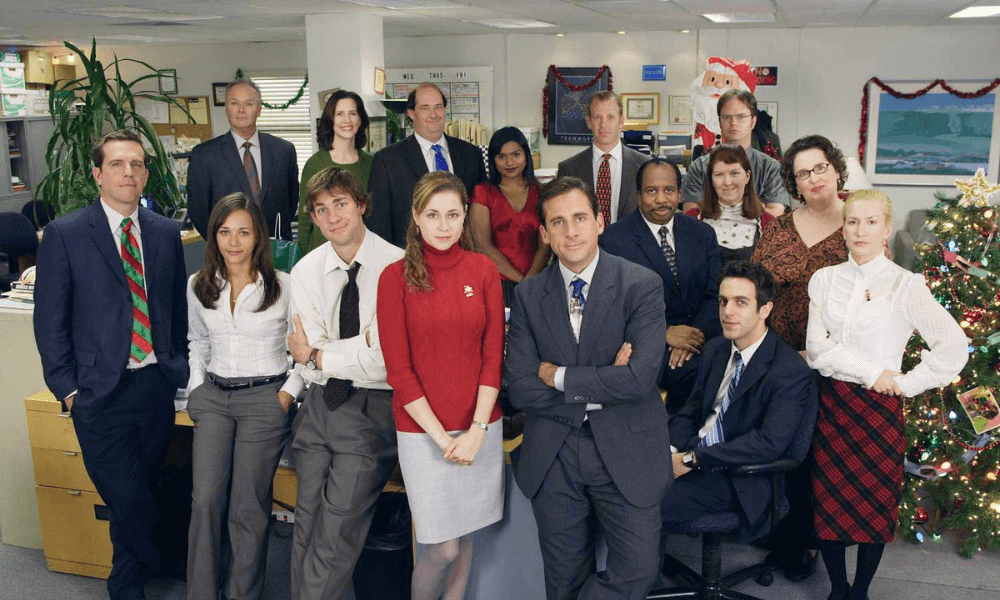 Group of office workers posing for a photo with holiday decorations in the background.