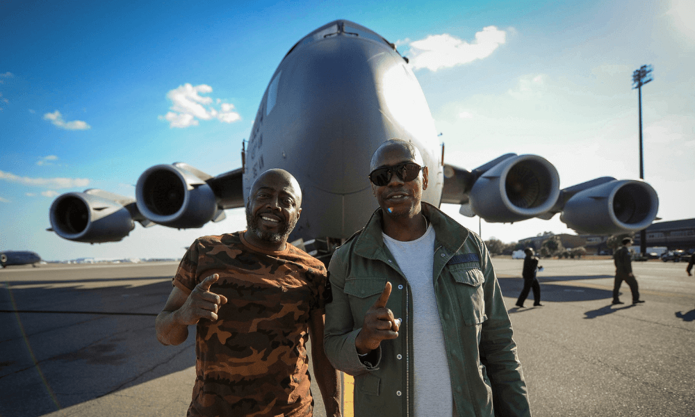 Two men standing in front of an airplane.