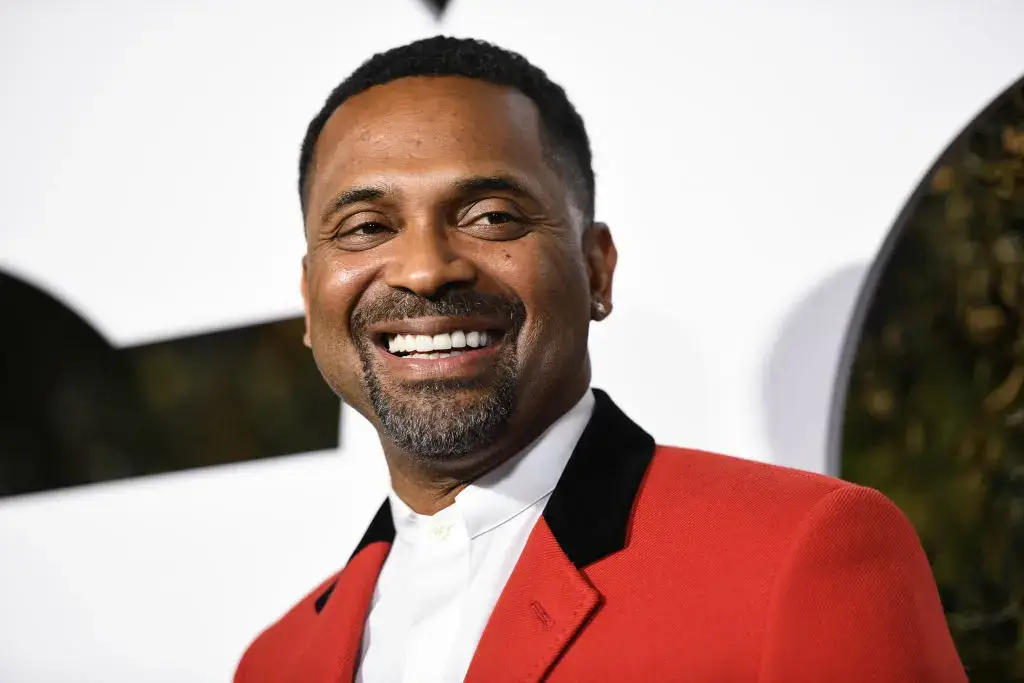 A man in a red blazer and white shirt smiling at an event.
