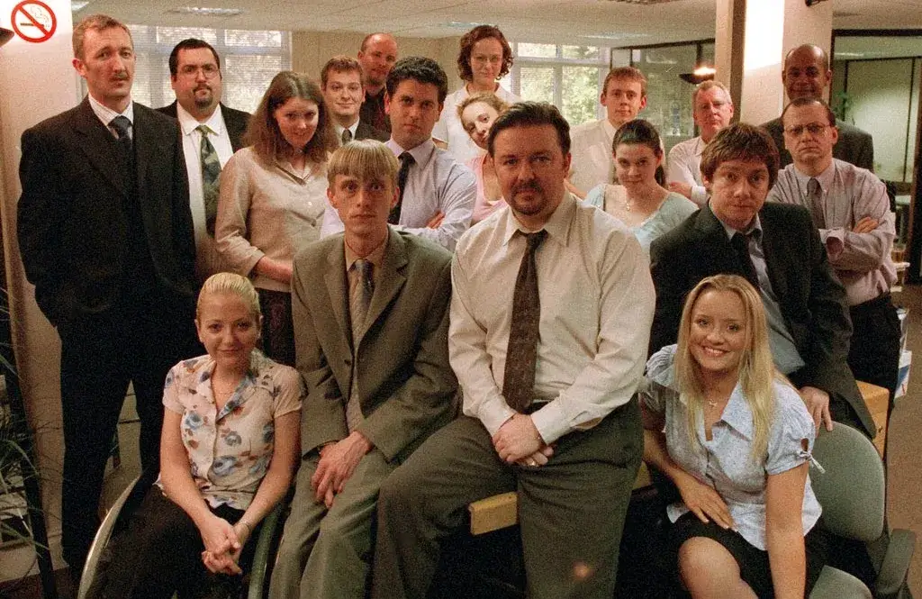 Group of office workers posing for a photo with mixed expressions.