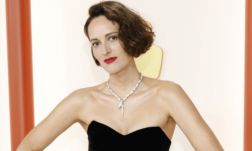 Young woman in a black strapless dress and an elegant diamond necklace posing at a formal event.